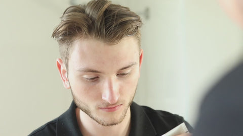 Illustrative video of a person applying skincare across the face in front of a mirror.