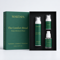 The Comfort Ritual: three products fitted inside an open black presentation box, beside its emerald lid.