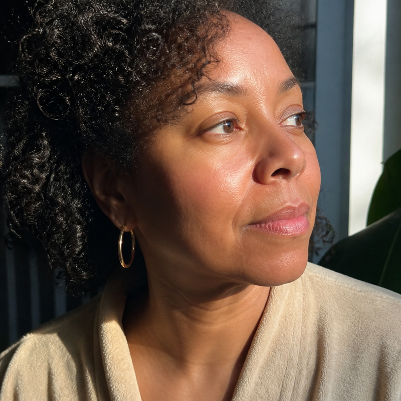 Portrait of a woman with curly hair in warm daylight.
