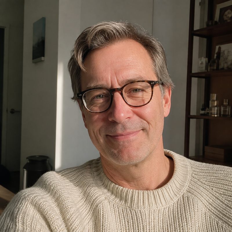 Portrait of a man wearing glasses and a cream knit jumper.