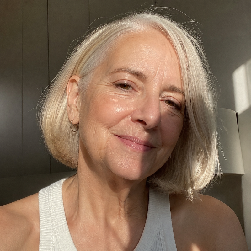 Portrait of a silver-haired woman in soft window light.