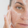 Illustrative close-up video of a person spreading cream over a cheek and forehead.