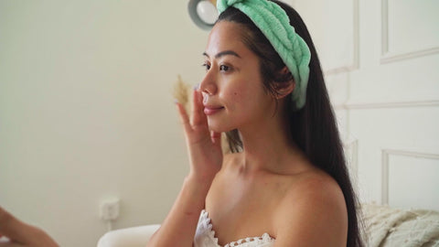 Illustrative video of a person applying skincare beneath an eye while looking in a hand mirror.