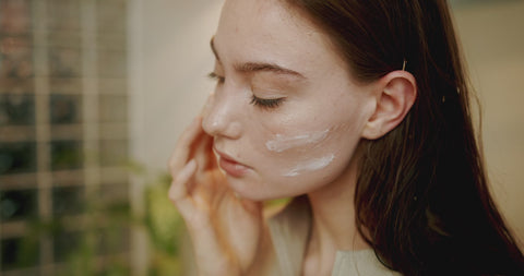 Illustrative video of a person smoothing cream over a cheek with fingertips.